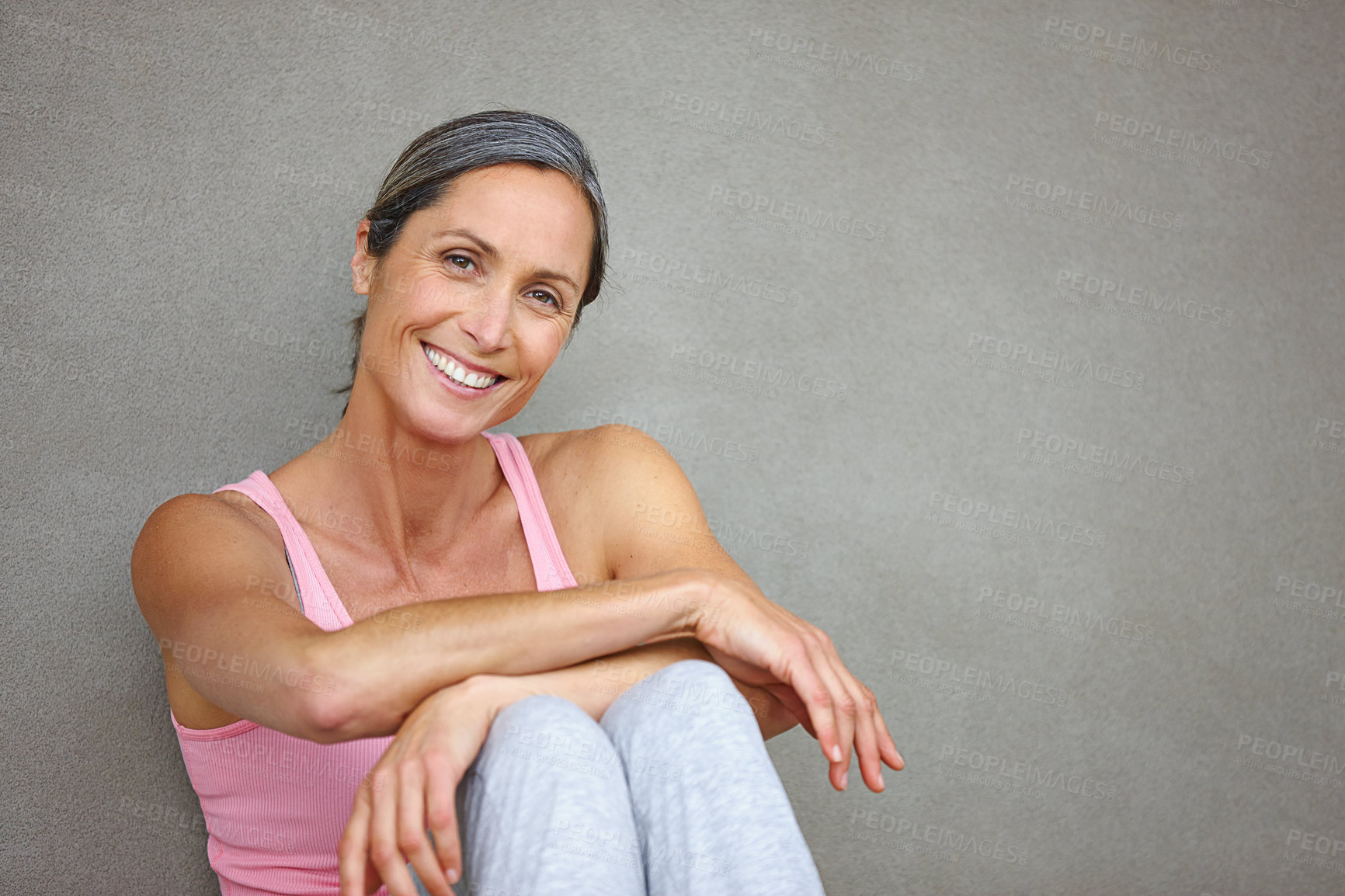 Buy stock photo Portrait of an attractive mature woman in gymwear sitting against a gray wall