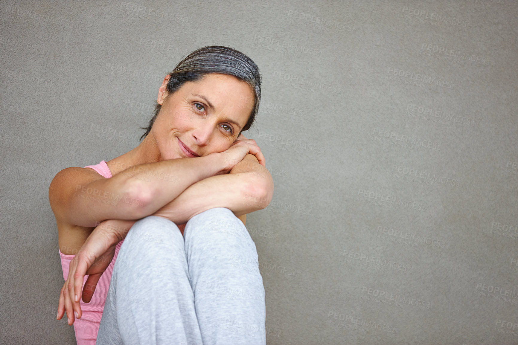 Buy stock photo Portrait of an attractive mature woman in gymwear sitting against a gray wall