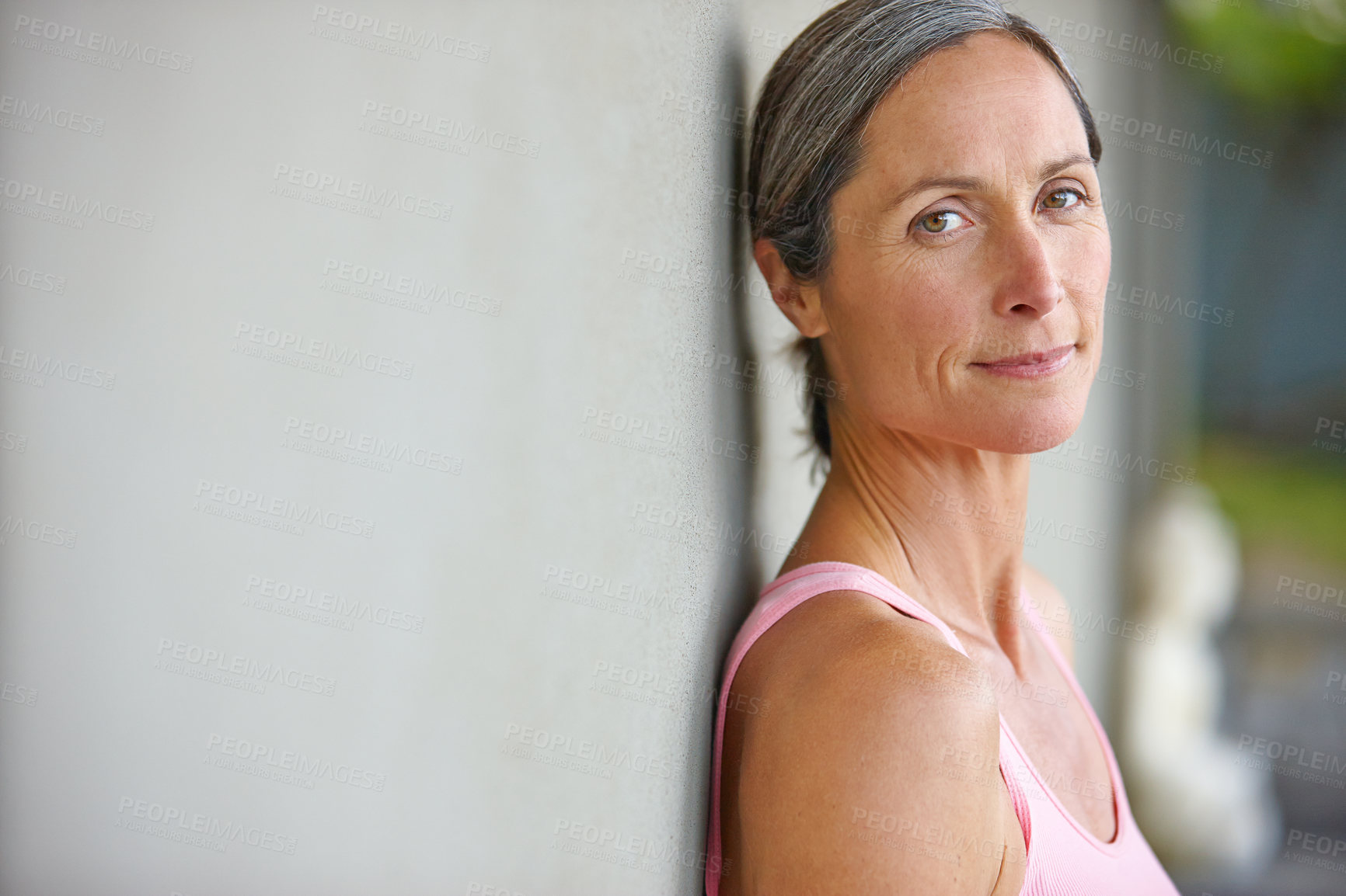 Buy stock photo Portrait of an attractive mature woman in gymwear leaning against a gray wall