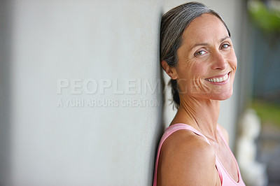 Buy stock photo Portrait of an attractive mature woman in gymwear leaning against a gray wall