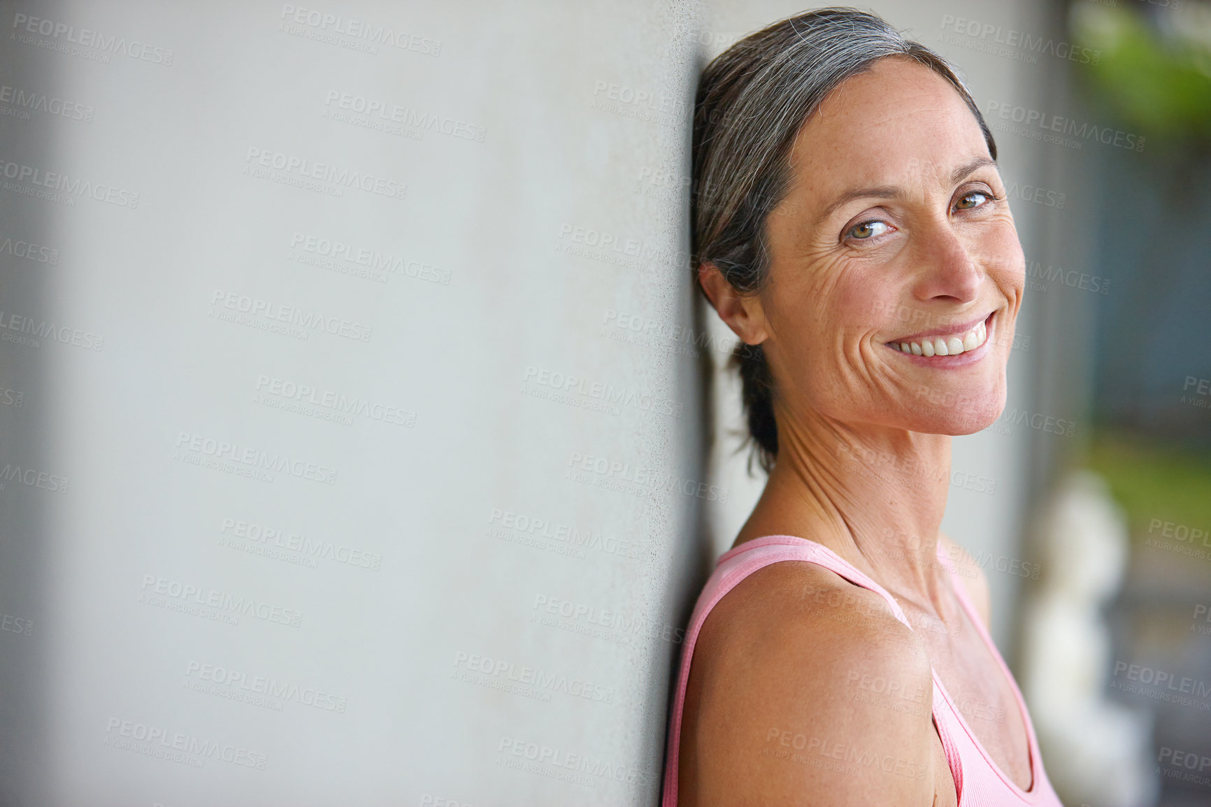 Buy stock photo Portrait of an attractive mature woman in gymwear leaning against a gray wall