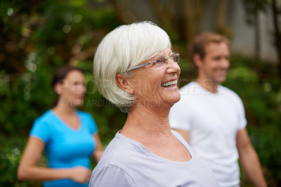 Buy stock photo Shot of a senior woman laughing outdoors with fellow fitness class members