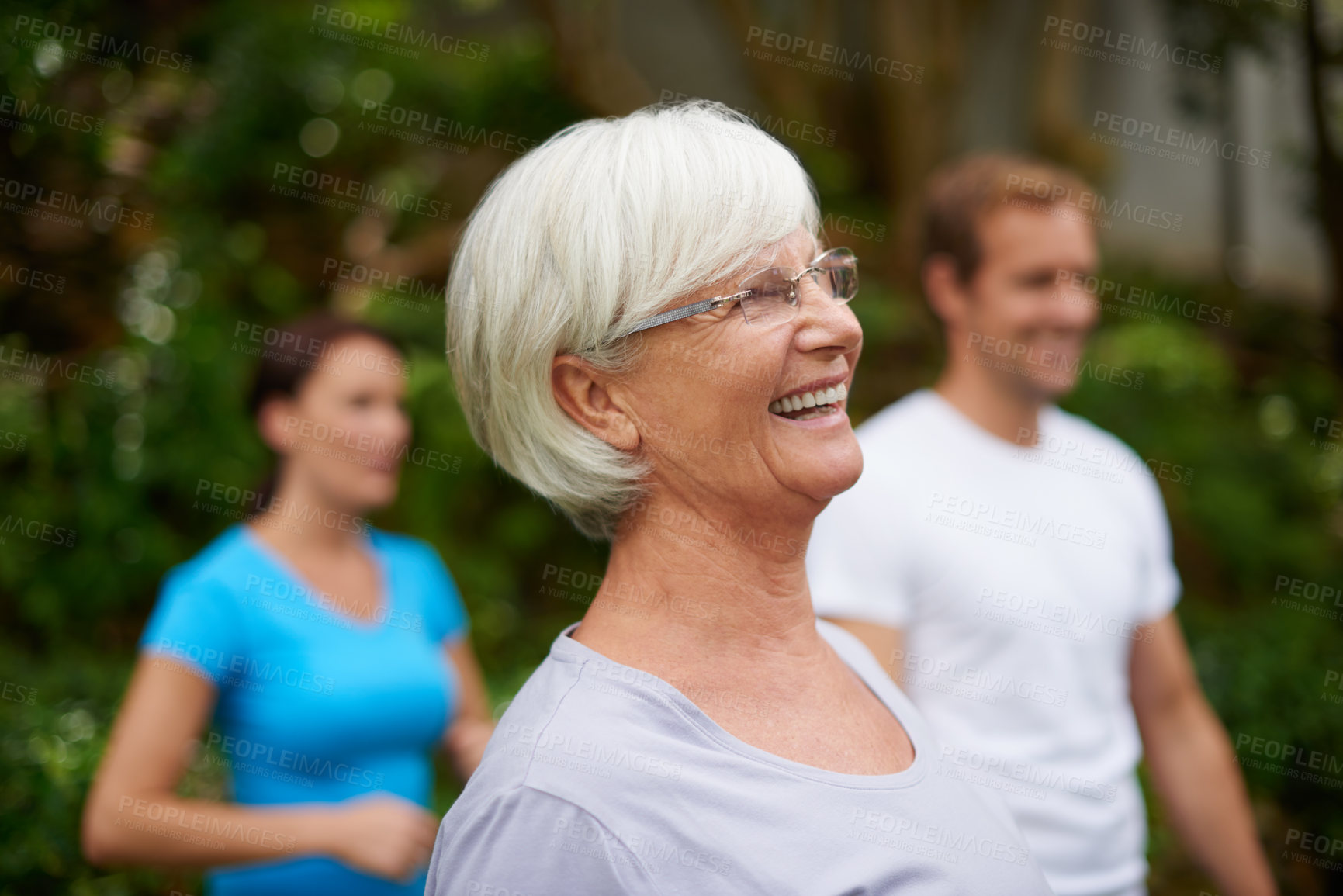 Buy stock photo Shot of a senior woman laughing outdoors with fellow fitness class members
