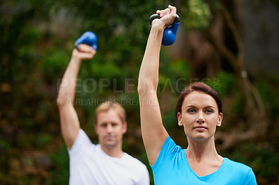 Buy stock photo Shot of a man and woman using kettle bell weights in an outdoor exercise class
