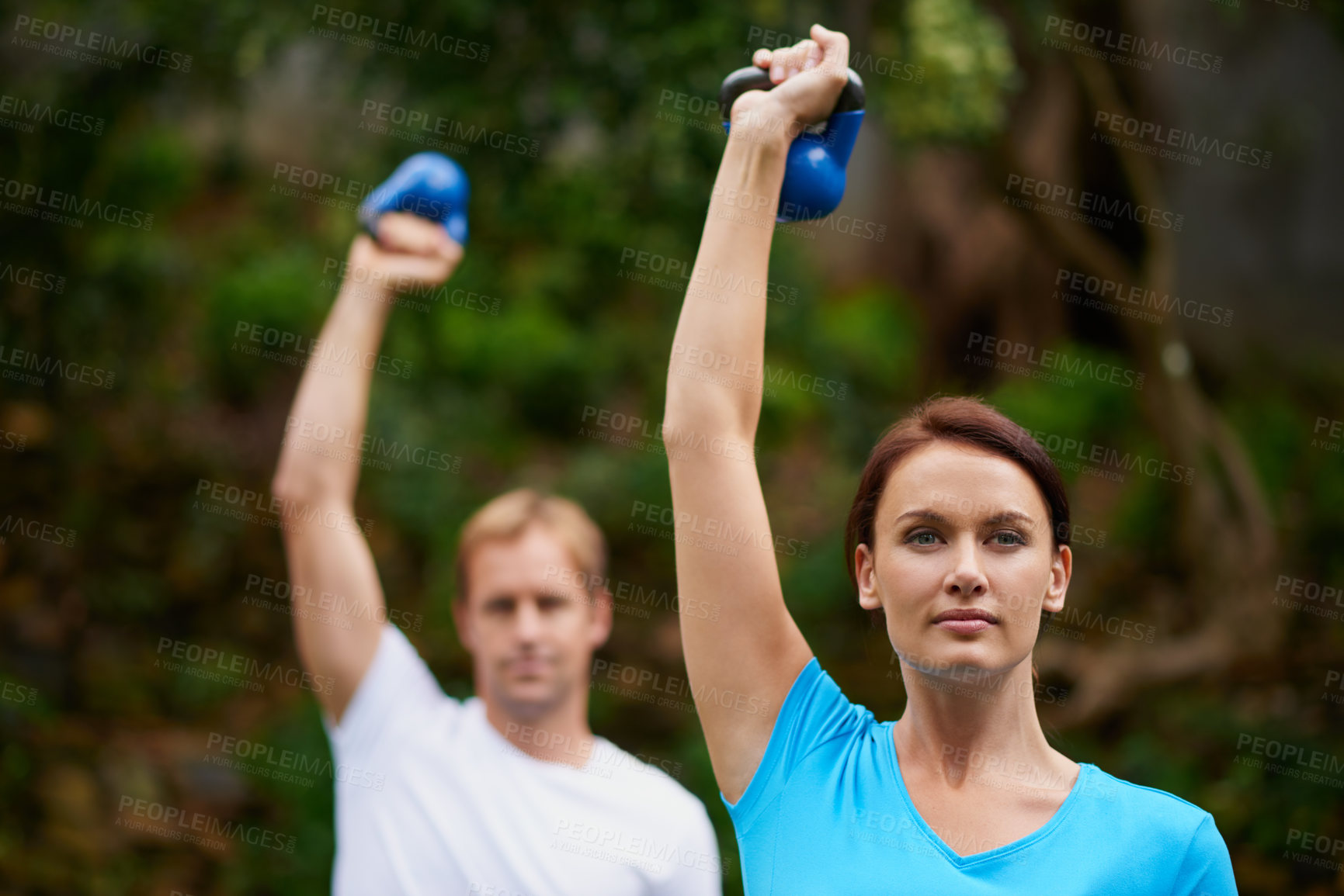Buy stock photo Shot of a man and woman using kettle bell weights in an outdoor exercise class