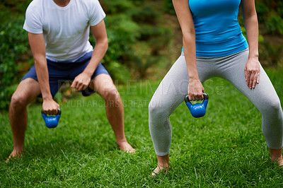 Buy stock photo Cropped shot of a man and woman using kettle bell weights in an outdoor exercise class