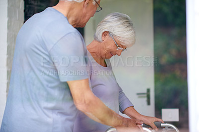 Buy stock photo Shot of a senior man helping his wife with her orthopedic walker