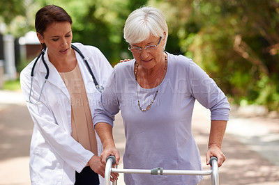 Buy stock photo Outdoor shot of a doctor helping a senior woman to walk with an orthopedic walker