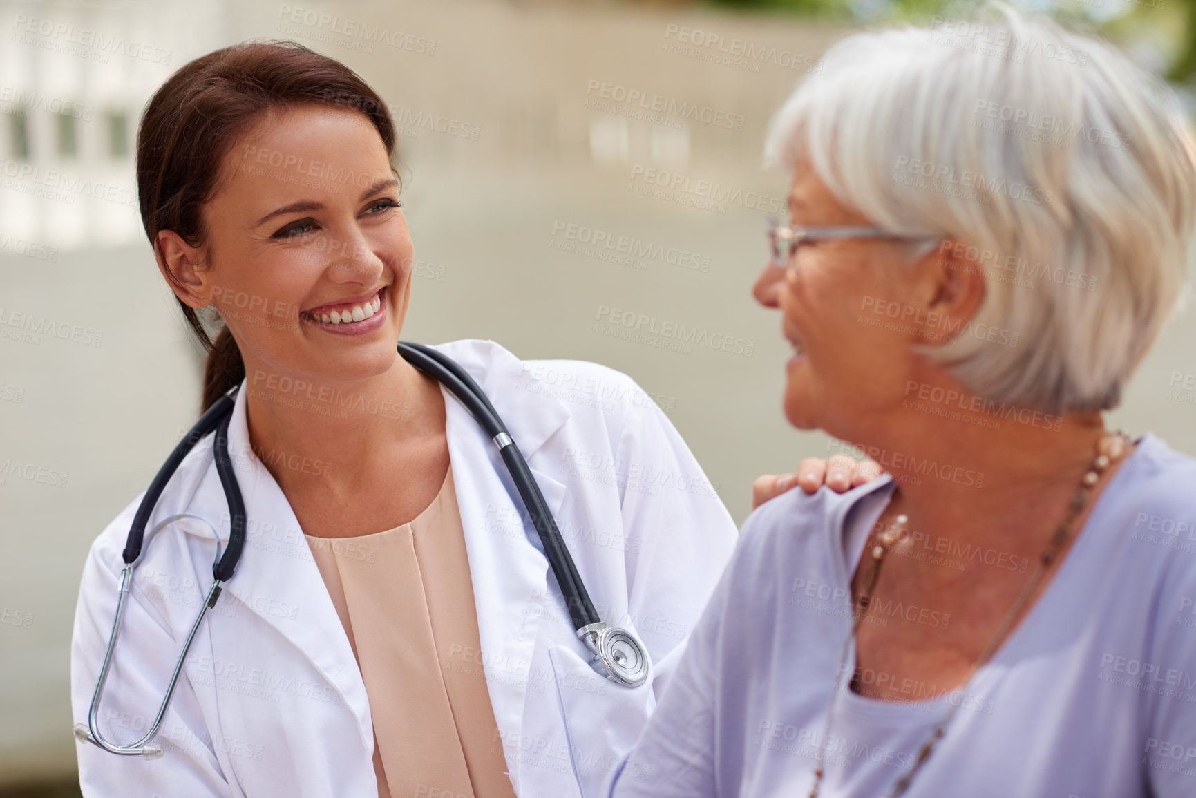 Buy stock photo Shot of a smiling doctor conversing with a senior patient