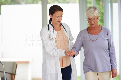 Buy stock photo Shot of a senior woman walking carefully with help from her doctor