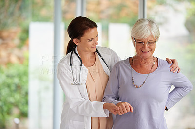 Buy stock photo Shot of a senior woman standing with help from her doctor