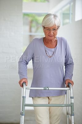 Buy stock photo Shot of a senior woman walking carefully with the help of a walker
