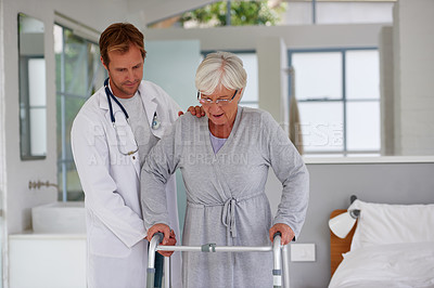 Buy stock photo Shot of a senior woman walking carefully with help from her doctor and an orthopedic walker