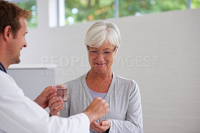 Buy stock photo Shot of a doctor handing some medication over to a senior patient