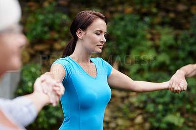 Buy stock photo Shot of a young woman holding hands with the people she's doing yoga with