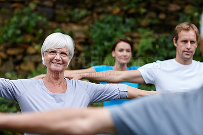 Buy stock photo Shot of a senior woman doing yoga with other people outdoors
