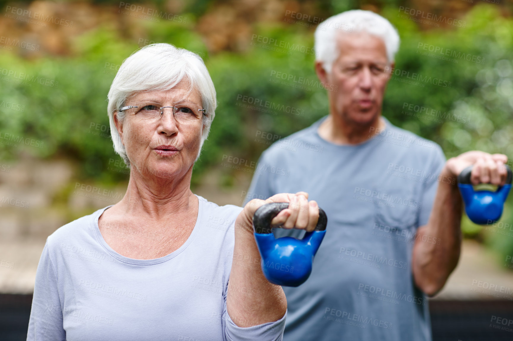 Buy stock photo Shot of a senior couple training with light weights outdoors