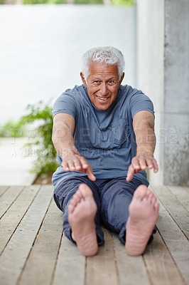 Buy stock photo Shot of a senior man stretching to touch his toes outdoors