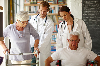 Buy stock photo Shot of two senior people being helped by nursing staff 