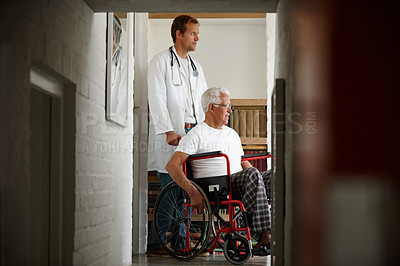 Buy stock photo Shot of a male doctor standing with his senior patient who's in a wheelchair