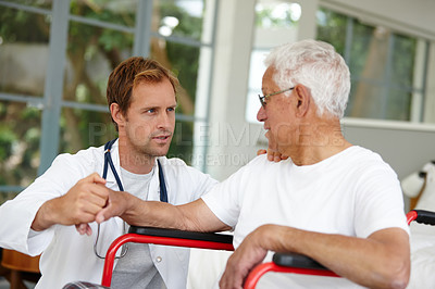 Buy stock photo Shot of a handsome male doctor talking to his senior patient who's in a wheelchair