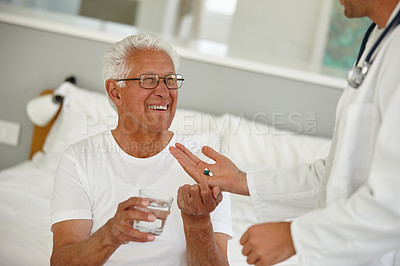 Buy stock photo Shot of a doctor giving his senior patient a dose of medicine at an assisted living facility