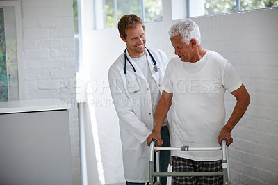Buy stock photo Shot of a male doctor assisting his senior patient who's using a walker for support