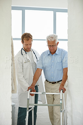 Buy stock photo Shot of a male doctor assisting his senior patient who's using a walker for support
