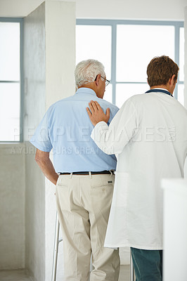 Buy stock photo Rearview shot of a male doctor supporting his senior patient who's using a walker