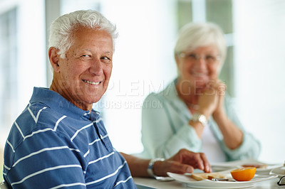 Buy stock photo Portrait of a senior man having breakfast with his wife in the background