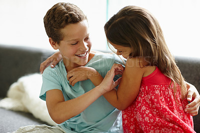 Buy stock photo Shot of a brother and sister tickling each other while on the sofa