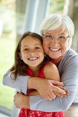 Buy stock photo Portrait of a senior woman embracing her granddaughter at home