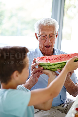Buy stock photo Shot of a little boy handing his grandfather a slice of watermelon