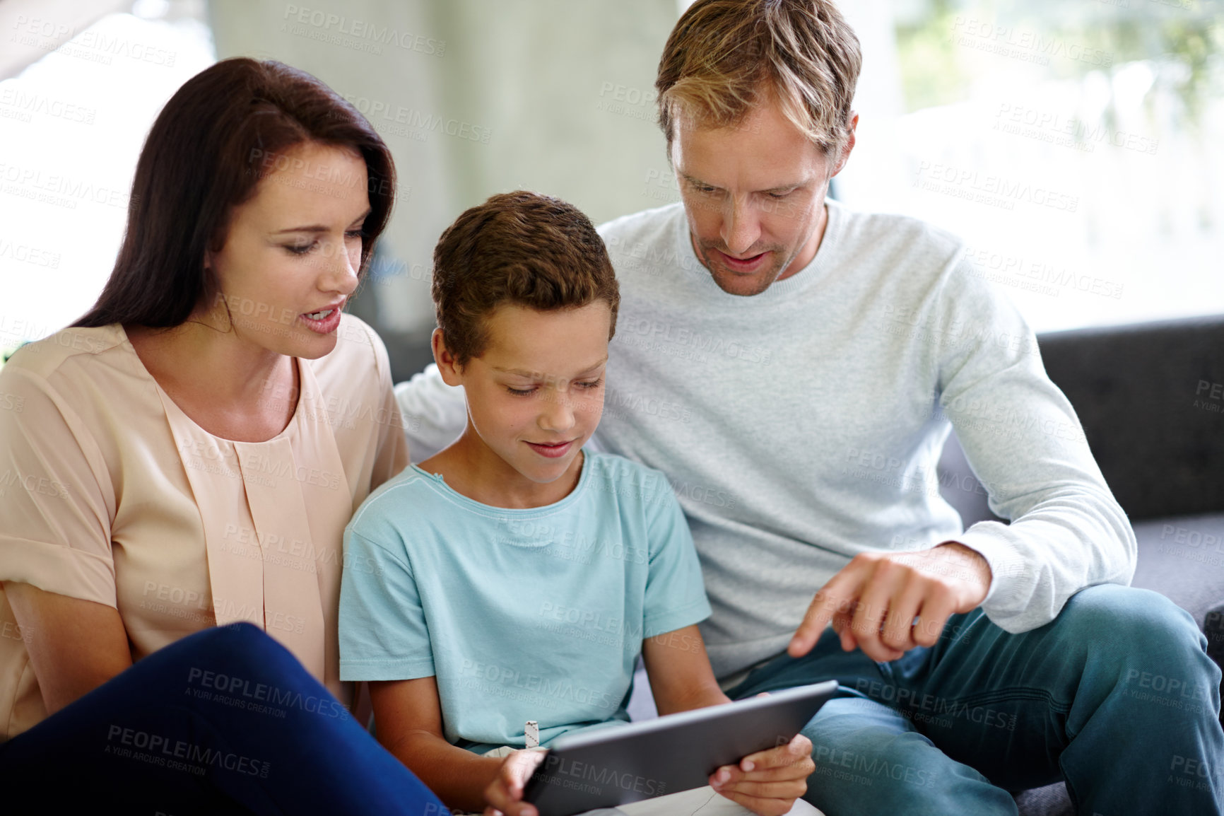 Buy stock photo Shot of a family using a digital tablet while sitting on the sofa at home