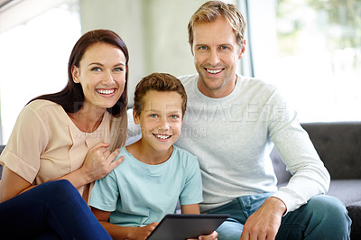 Buy stock photo Portrait of a family sitting together on the sofa with a digital tablet