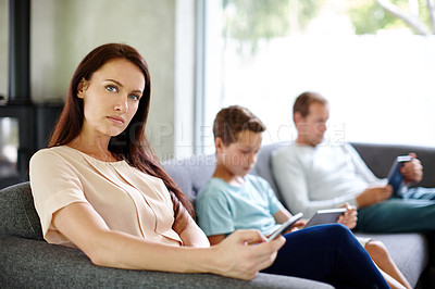 Buy stock photo Shot of a family of three sitting separately on a sofa with their own digital devices