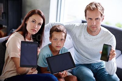 Buy stock photo Portrait of a family looking serious as they hold up their digital devices