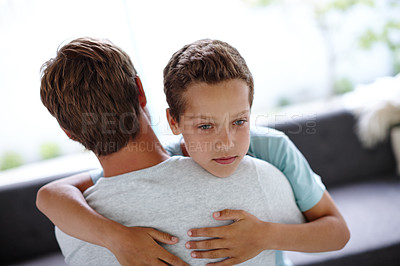 Buy stock photo Shot of a sad little boy hugging his father at home