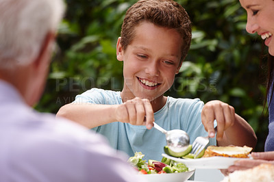 Buy stock photo Shot of a little boy having lunch with his family outside