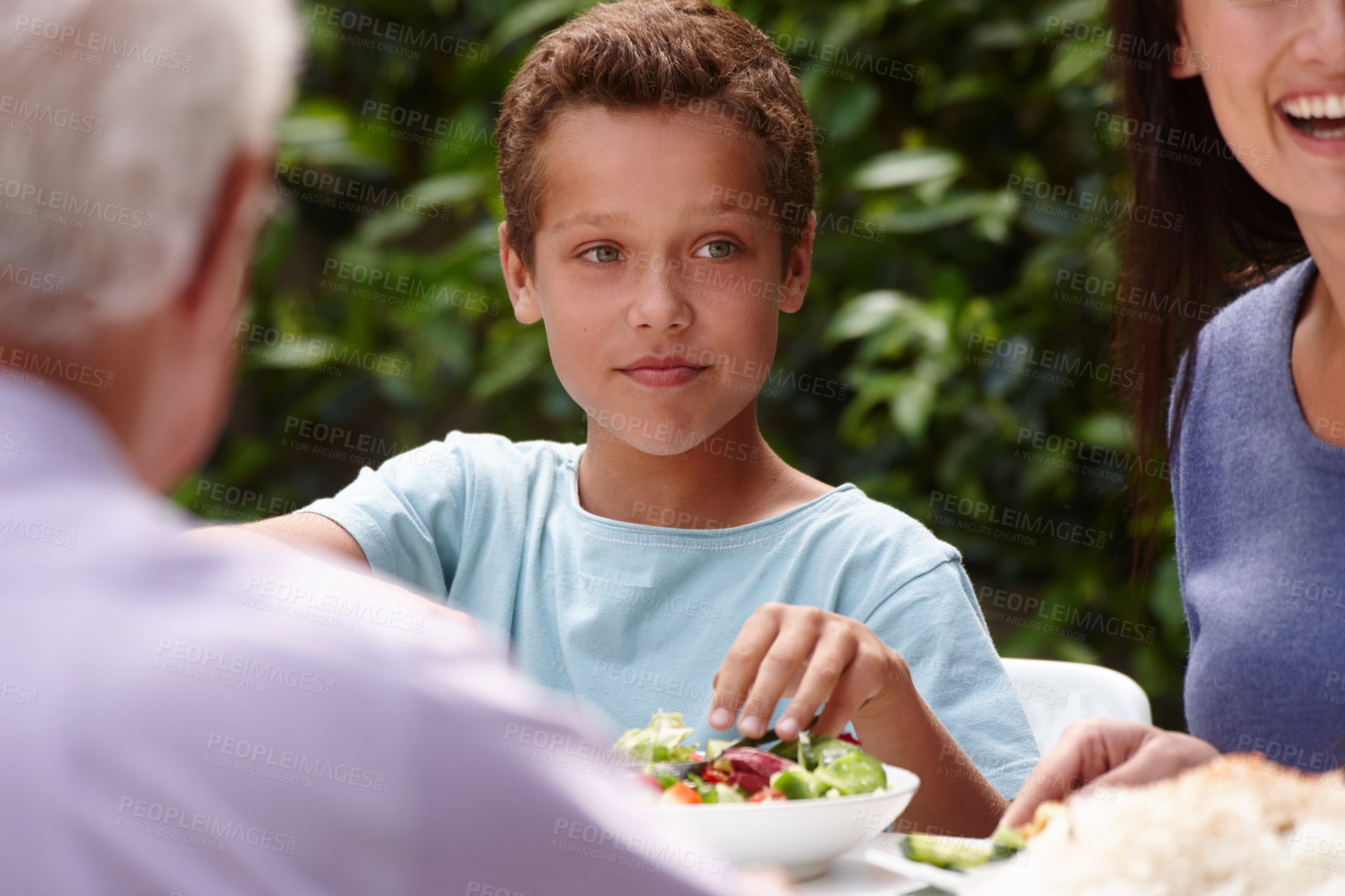 Buy stock photo Shot of a little boy having lunch with his family outside