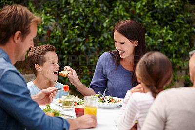 Buy stock photo Shot of a happy multi-generational family having a meal together outside