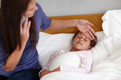Buy stock photo Shot of a mother calling the doctor while sitting by her sick little girl
