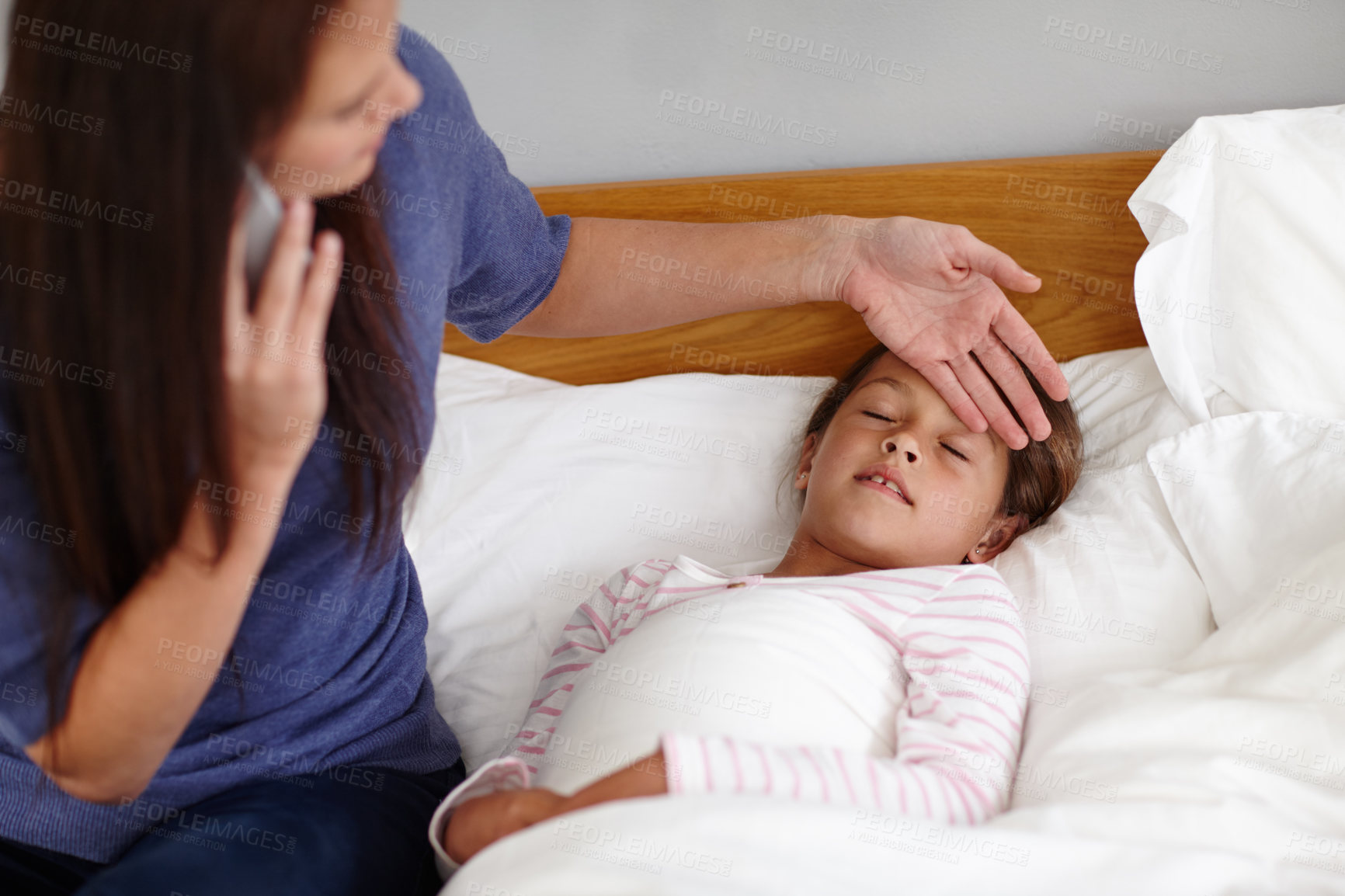 Buy stock photo Shot of a mother calling the doctor while sitting by her sick little girl