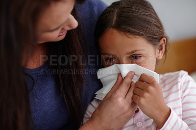Buy stock photo Shot of a mother helping her sick daughter to blow her nose