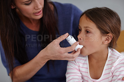 Buy stock photo Shot of a caring mother giving her daughter an asthma pump at home