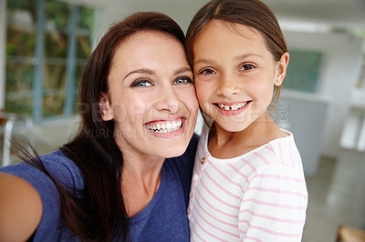Buy stock photo Shot of a mother and daughter taking a selfie at home