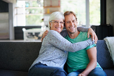 Buy stock photo Portrait of a senior woman embracing her son while sitting on the sofa at home