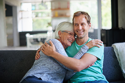 Buy stock photo Cropped shot of a senior woman embracing her son while sitting on the sofa at home