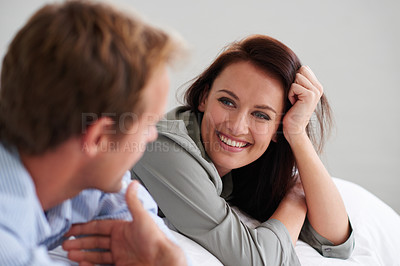 Buy stock photo Shot of a happy young couple lying on their bed at home