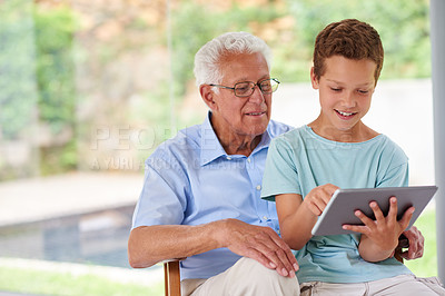 Buy stock photo A boy using a digital tablet with his grandfather